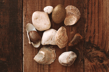 Close up decorative stones and seashells of different beige white gold shades on a blurred brown wooden table. Natural material. Top view