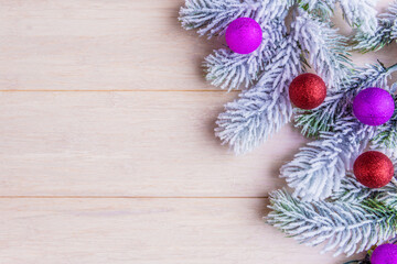 Frosty fir tree branches and decorative balls on wooden background with copy space