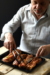 Selective focus. The chef puts the marinated pork ribs on a baking sheet. Barbecuing ribs.