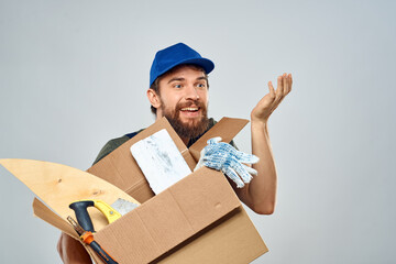 man in work uniform with box in hands tools lifestyle light background