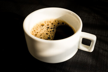 Xícara de café expresso sobre o tampo de madeira preta - Foto ao topo e perfil