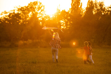 mothers and daughters in a field at sunset with an kite