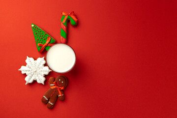 Fototapeta na wymiar Glass of milk and gingerbread biscuit on red background