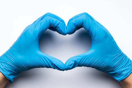 Hands in latex medical gloves making heart shape on white background