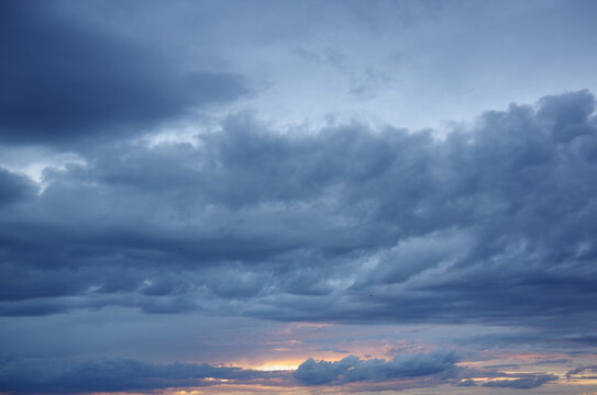 Dark storm clouds with colorful reflections of the setting sun. Scenic storm clouds lit by the last rays of the sunset. © Natalia