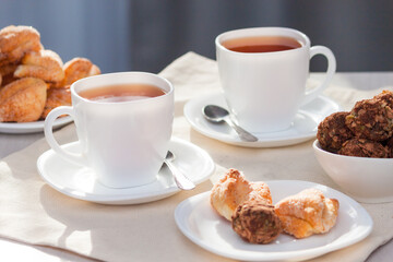 Fresh homemade sugar cookies with tea on white table with sun lights. Good morning or day concept.