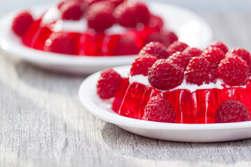 Fruit jelly with fresh raspberries. Healthy food. Summer dessert on grey table with sun light.