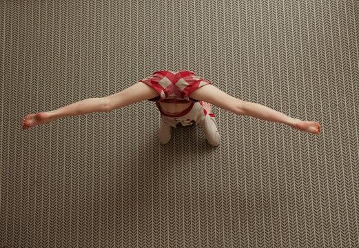 young teen girl wearing casual clothes working out in studio. Fit yogi girl doing advanced inversion and arm-balance. Handstand. Vrischikasana. Full length. top view image