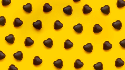 Chocolate heart shaped chocolates on red background in a row. Creative pattern for Valentine Day. Top view.