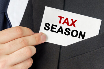 Businessman holds a card with the text - TAX SEASON