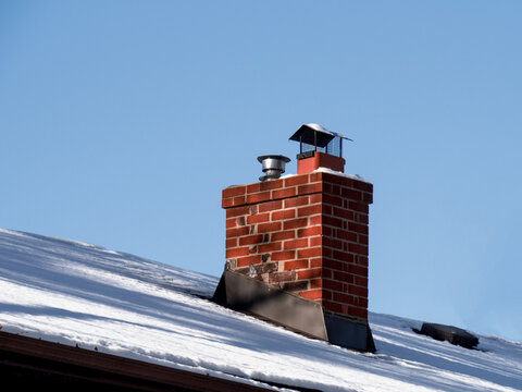 an old brick chimney on a snow covered rooftop