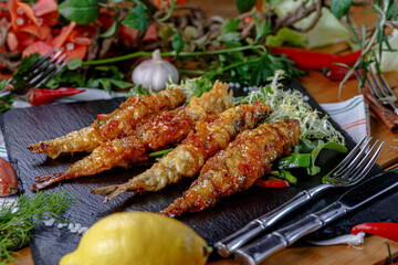 Deep-fried langoustines in batter lie on a plate in a restaurant.