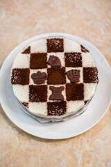Sponge cake with butter cream. Cake in the form of a chessboard. A gift for the day of a chess player. Cake with chocolate cakes and white pudding. Appetizing dessert.