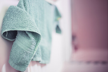 Dirty and wet olive green towel in a bathroom on a radiator