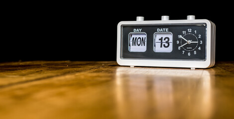 Monday 13th day of the month, Monday thirteenth - vintage alarm clock with date on a wooden table - copy space