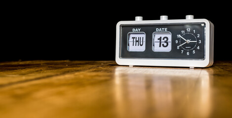 Thursday 13th day of the month, Thursday thirteenth - vintage alarm clock with date on a wooden table - copy space