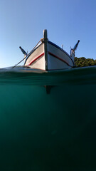 Sea level split underwater photo of traditional fishing boat anchored in crystal clear turquoise...