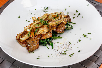 Roast beef liver with spinach and onions on a plate