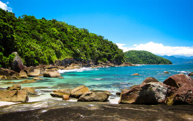 Fototapeta na wymiar Rocks and blue water in a brazilian paradise beach - Praia das Conchas - Ubatuba - SP
