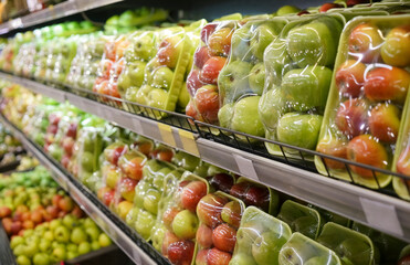 Green and red apples packed under plastic film.