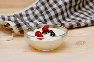 natural yogurt in a bowl decorated with raspberries and currants close-up