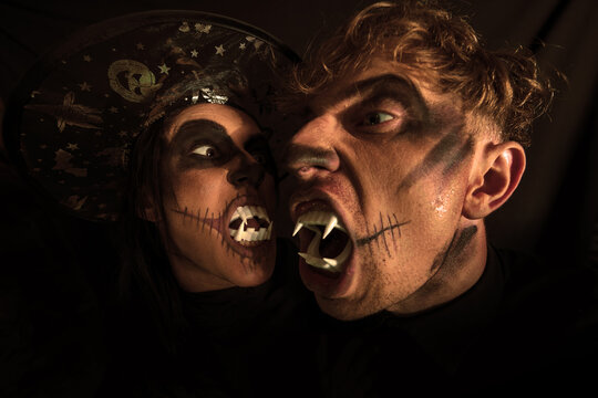 Couple with dark skull makeup on black background. Halloween face art. Fashion photo. Zombie.

