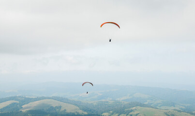 Fototapeta na wymiar A man is flying on a paraglider in clouds and fog. Summer sports, active lifestyle, activity in mountains 