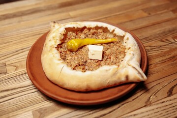 Top view on tasty traditional Adjarian Khachapuri - open baked pie with meat and pepperyolk on wooden tray. Traditional georgian food