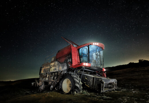 Abandoned tractor under a starry sky.