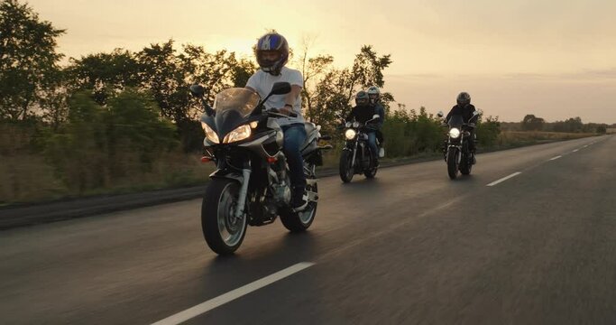 A group of bikers travel on motorcycles, ride on the highway in the evening before sunset