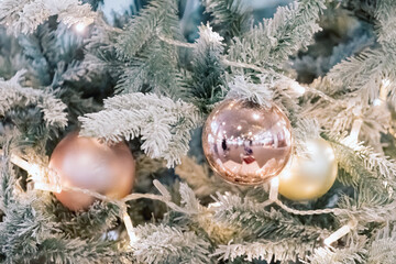 Balls and garlands hanging on pine branches on festive backdrop. Golden baubles on spruce tree. Christmas background. Merry Christmas and Happy New Year holiday postcard. Festive decoration
