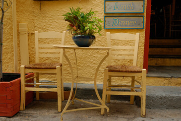 stolik i dwa krzesła przed drzwiami restauracji z napisem 