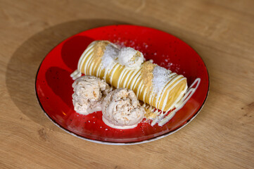 yellow pancake topped with vanilla topping and two scoops of ice cream. 
pancake - a real calorie bomb