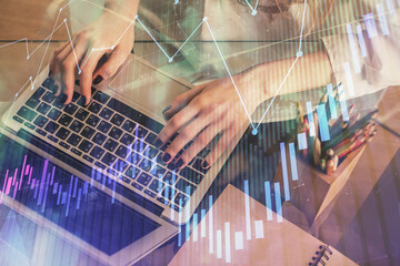 Double exposure of woman hands typing on computer and forex chart hologram drawing. Stock market...