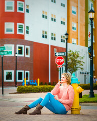 A thoughtful student girl sitting on the city street under the One Way and Stop sign, decision...