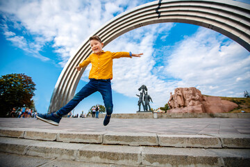 boy in a yellow shirt jumping from the steps on the street on a sunny day © popovatetiana