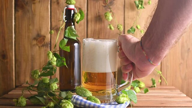 Beer. Cold Craft light Beer in a glass with water drops. Pint of Beer close up on a wooden background. Beer is pouring from the bottle. Border design. High quality 4k footage