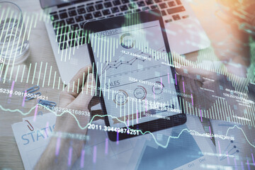 Double exposure of man's hands holding and using a digital device and forex graph drawing. Financial market concept.