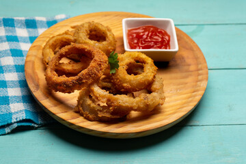 Onion rings with ketchup on turquoise background