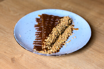 prelijepo dekorisani kaloricni palacinak pun čokolade. 
palacinak na plavom tanjiru sa mnogo različith preljeva od čokolade.