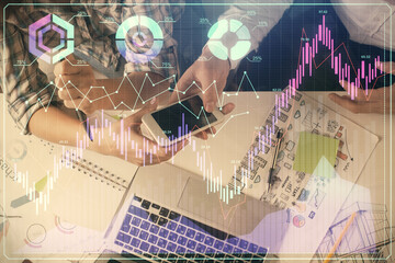 Double exposure of forex graph drawing and man and woman working together holding and using a mobile device. Trade concept.