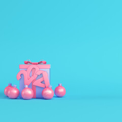 Pink present box with 2021 figures and christmas baubles on bright blue background in pastel colors