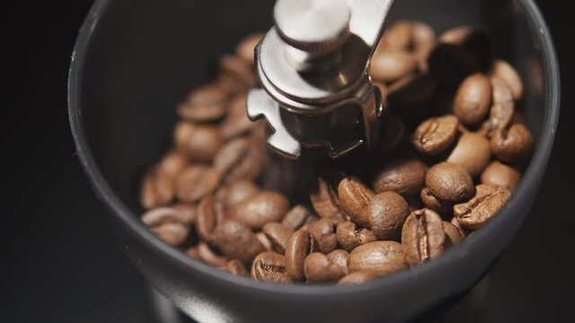 Vintage manual coffee grinder with falling coffee beans, close up