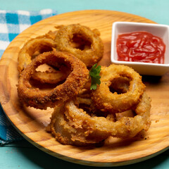 Onion rings with ketchup on turquoise background