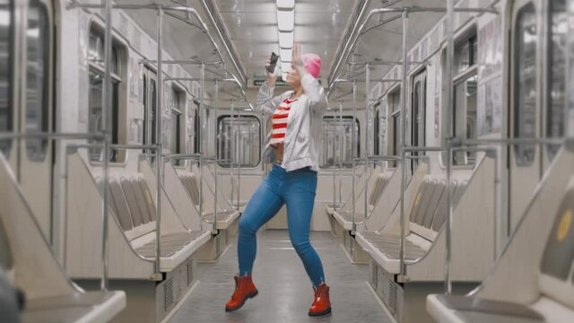 The Funny Attractive Joyful Blonde Girl Dancing In A Subway Car In Underground Metro. Woman Rejoices At The Success In The Train Public Transport