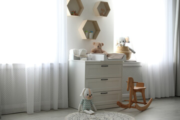 Beautiful baby room interior with toys and modern changing table