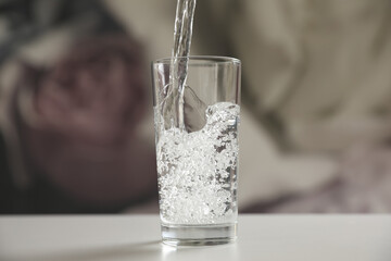 Pouring water into glass on table against blurred background
