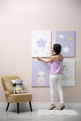 Fototapeta na wymiar Decorator hanging picture on pink wall. Children's room interior design