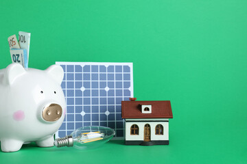 Composition with solar panel and piggy bank on white background