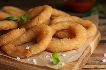 Delicious onion rings on wooden table, closeup